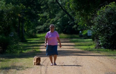 A woman walking her dog on country road