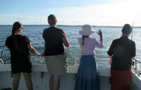 4 women fishing off back of boat on bay